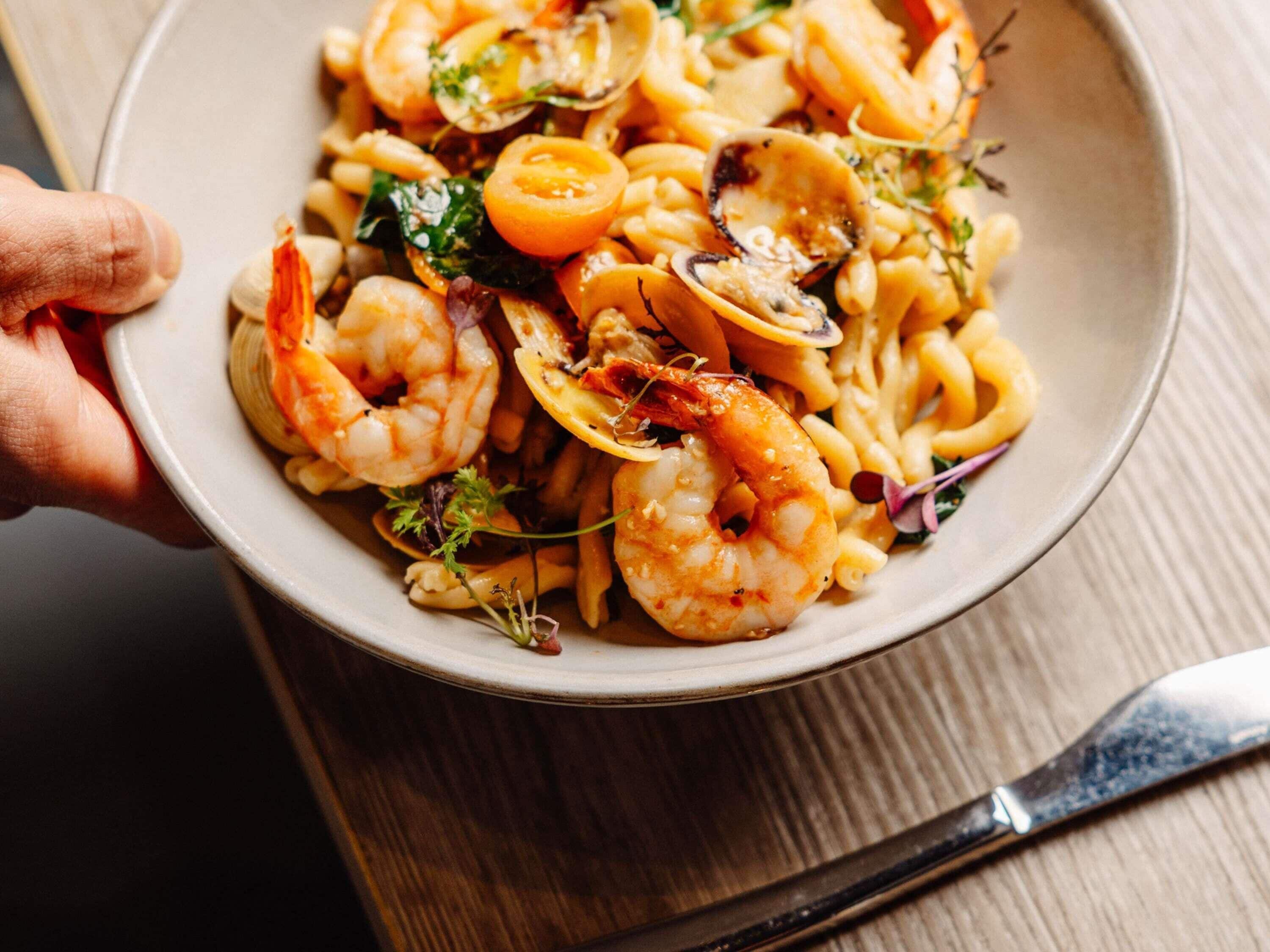 A bowl of pasta with shrimp and lemon slices.