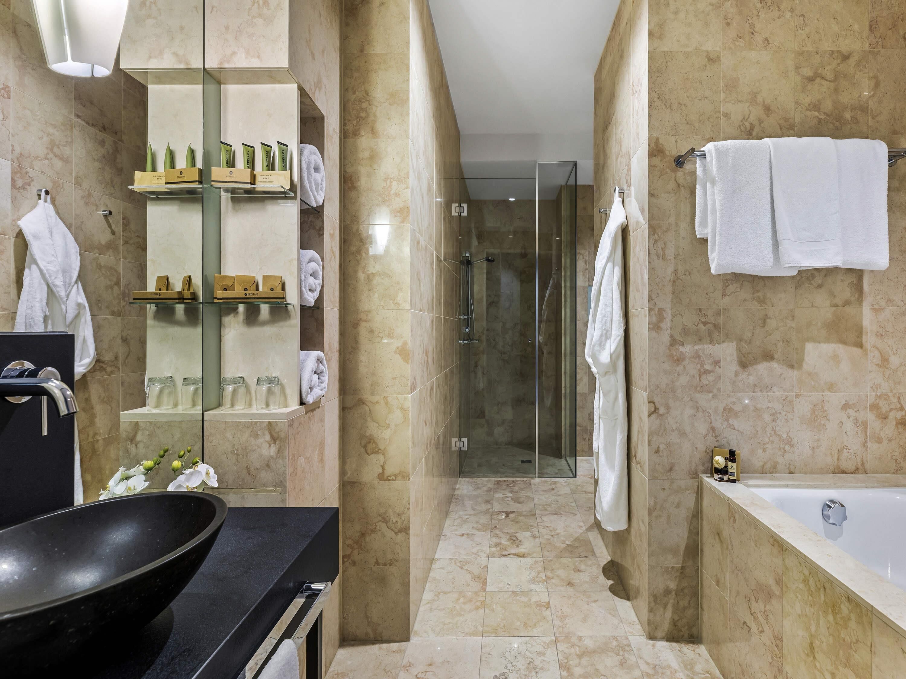 A modern bathroom with a glass-enclosed shower, a bathtub, and a vanity with a black sink.