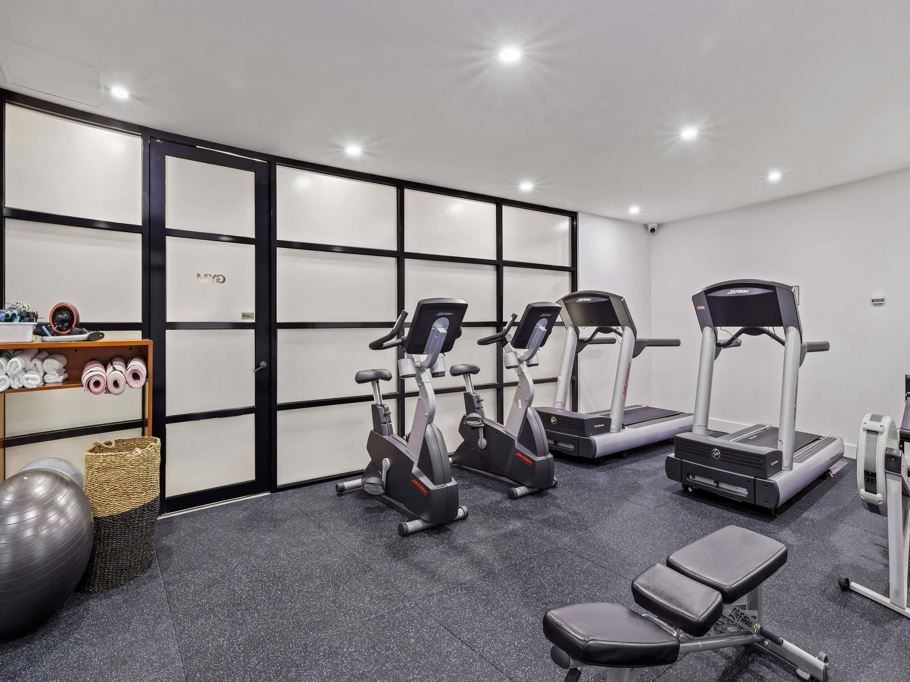 A gym with stationary bikes, treadmills, and a bench.
