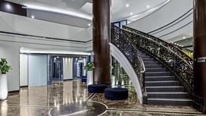A modern lobby with a curved staircase, marble flooring, and a large chandelier. - Peppers Waymouth Adelaide (Adelaide)