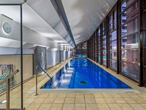 A long indoor swimming pool with a tiled floor, a clock on the wall, and large windows. - Peppers Waymouth Adelaide (Adelaide)