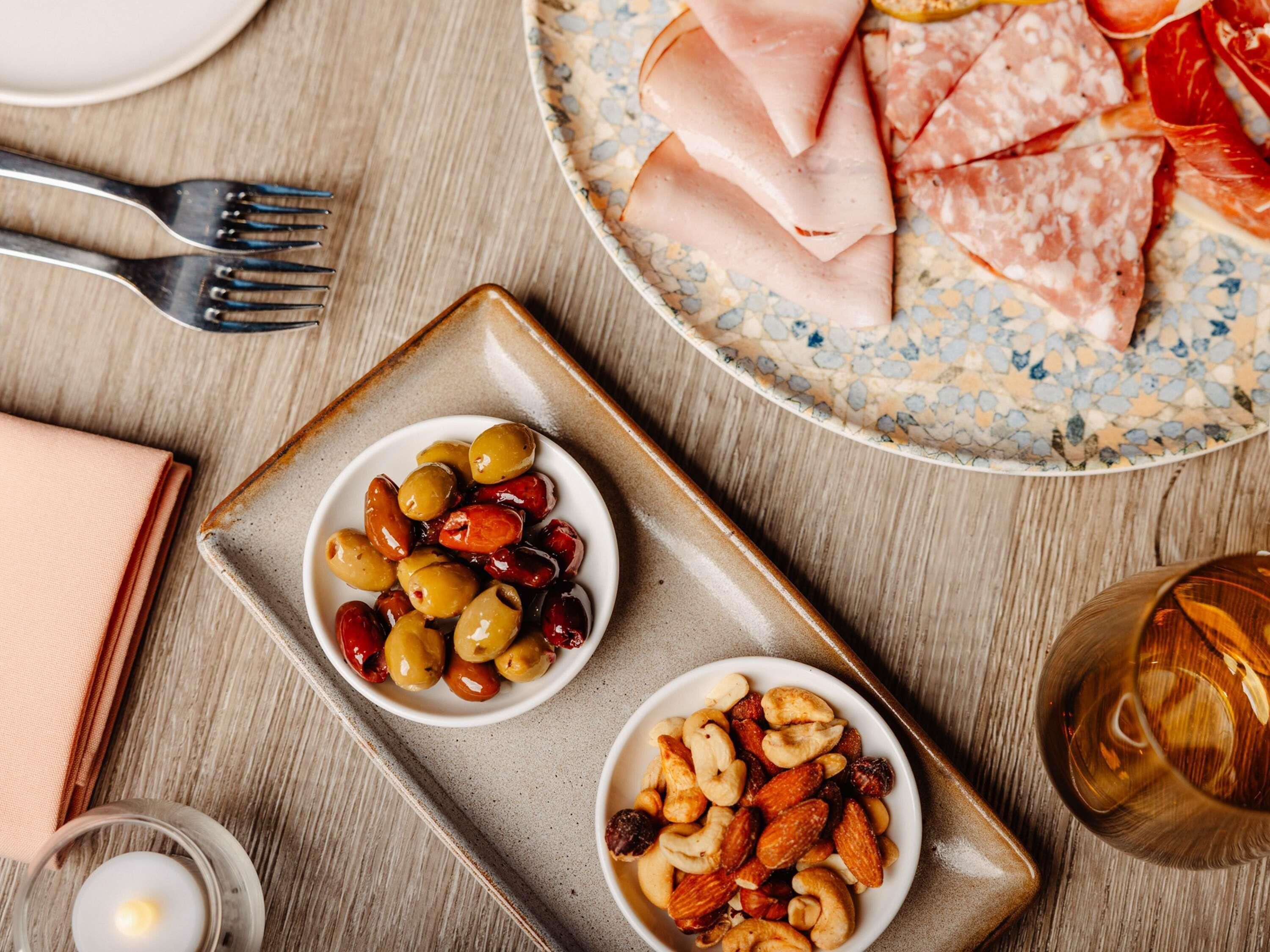 A dining table with plates of food, a candle, and a glass of drink.