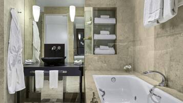 Un baño moderno con una bañera grande, un lavabo negro y un tocador con puertas de vidrio.
