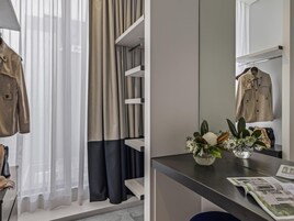 Une chambre moderne dotée d’une armoire intégrée, d’un miroir, d’un bureau agrémenté d’un vase de fleurs et d’un magazine.