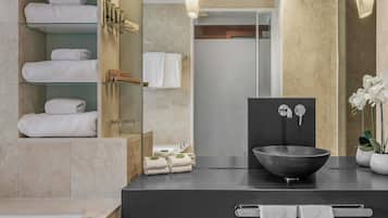 A modern bathroom with a black sink, a glass shower enclosure, and neatly arranged towels.