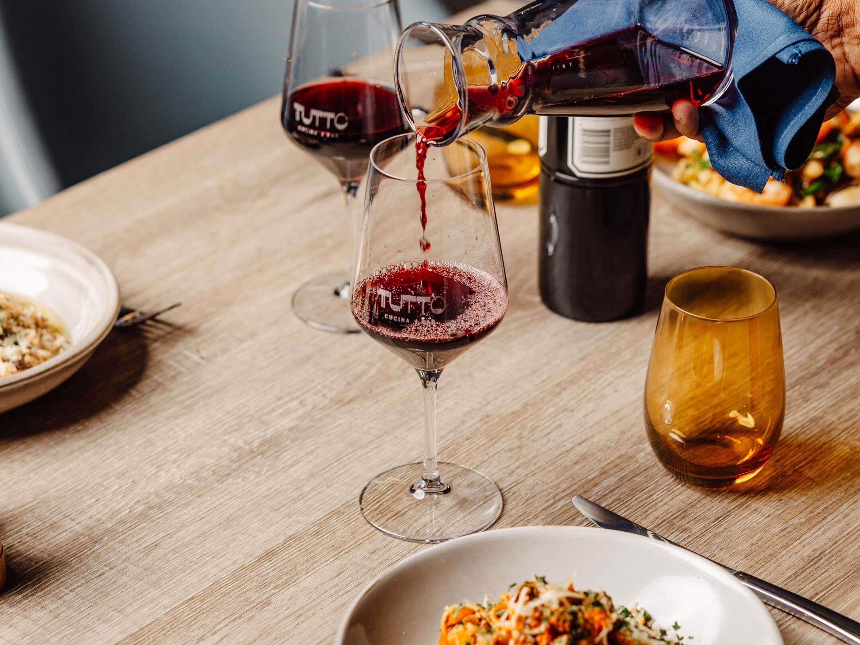 Ein Tisch mit Weingläsern, einer Flasche und einer Schüssel Essen.