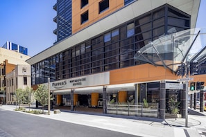Welcome to the Waymouth Hotel, located at the corner of Bentham Street, with a striking glass facade.