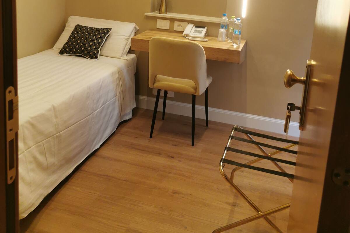 Una camera da letto piccola e luminosa con un letto singolo, una scrivania e una sedia.