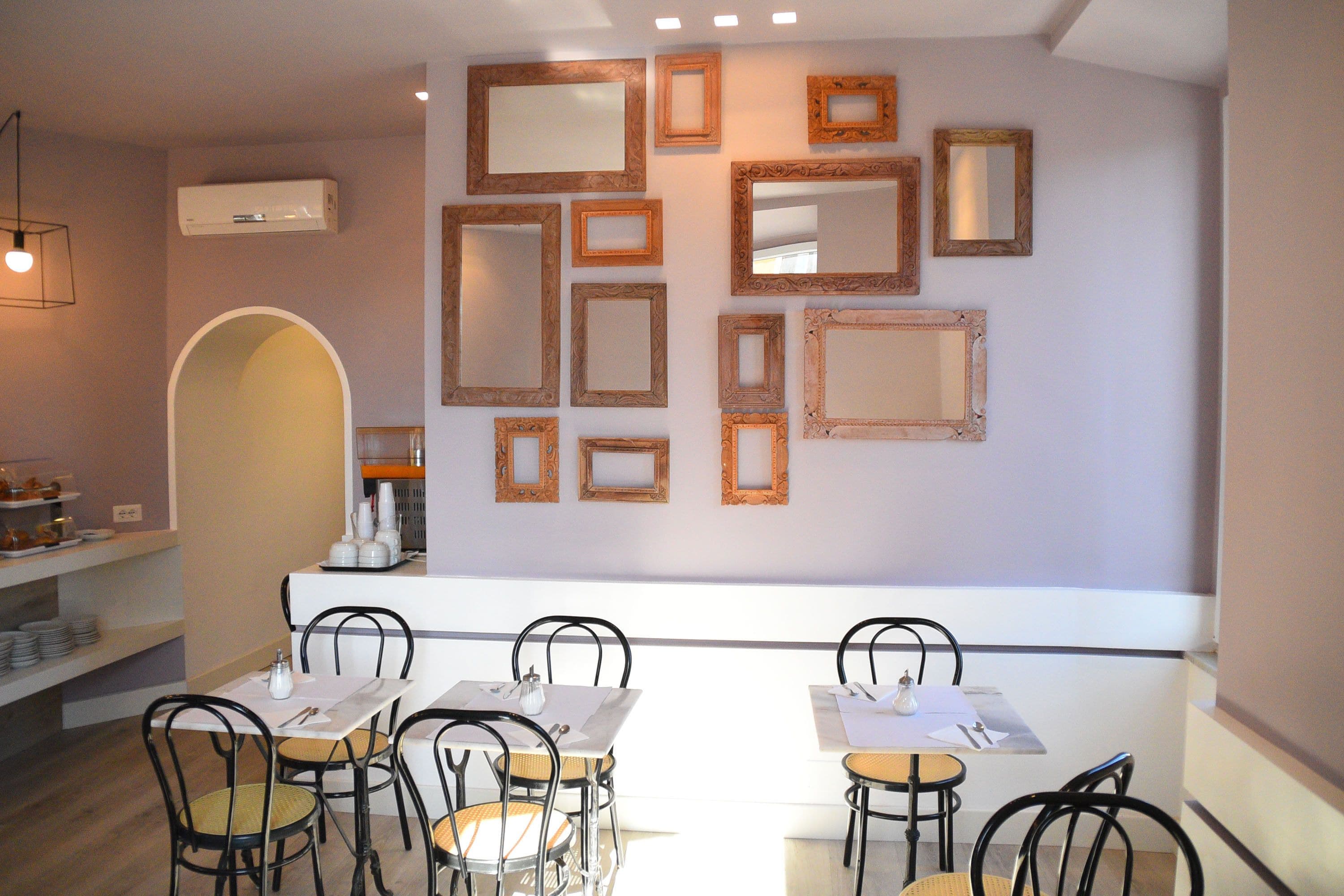 A dining area with a white table and chairs, a wall with multiple mirrors, and a shelf with plates.