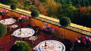 A terrace with outdoor seating, potted plants, and a view of a vineyard. - Castello della Castelluccia (Rome)