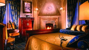 A room with a fireplace, a bed with blue and gold bedding, a wooden desk, and a chair. - Castello della Castelluccia (Rome)