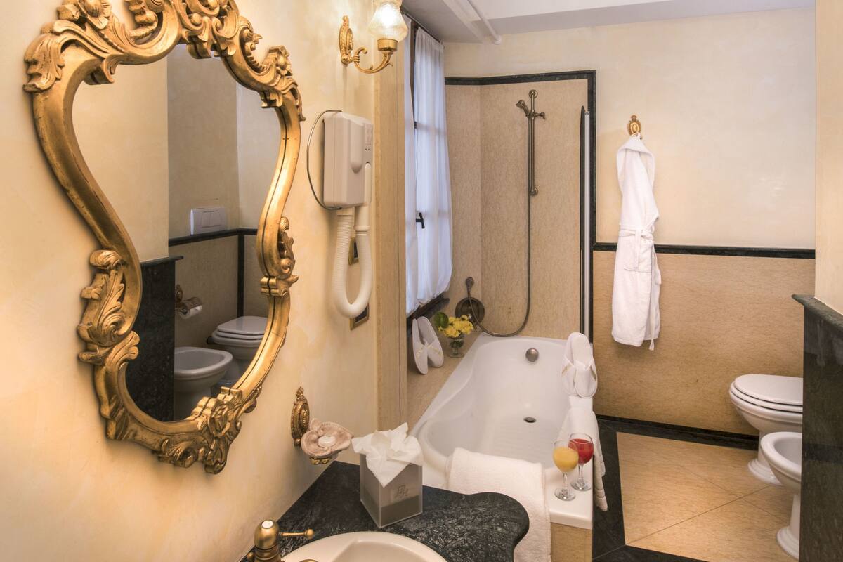 A bathroom with a large ornate mirror, a sink, a bathtub, and a shower.