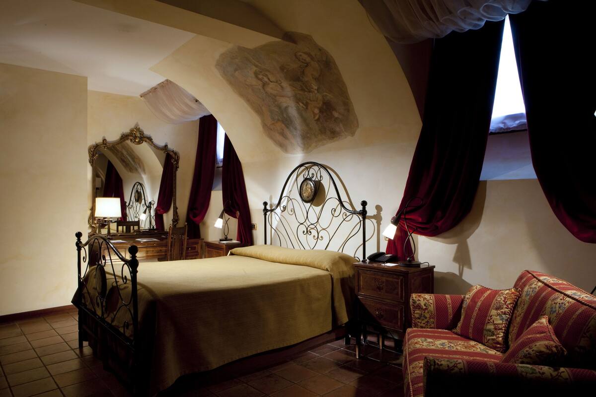A bedroom with a bed, a nightstand, a dresser, and a sofa.