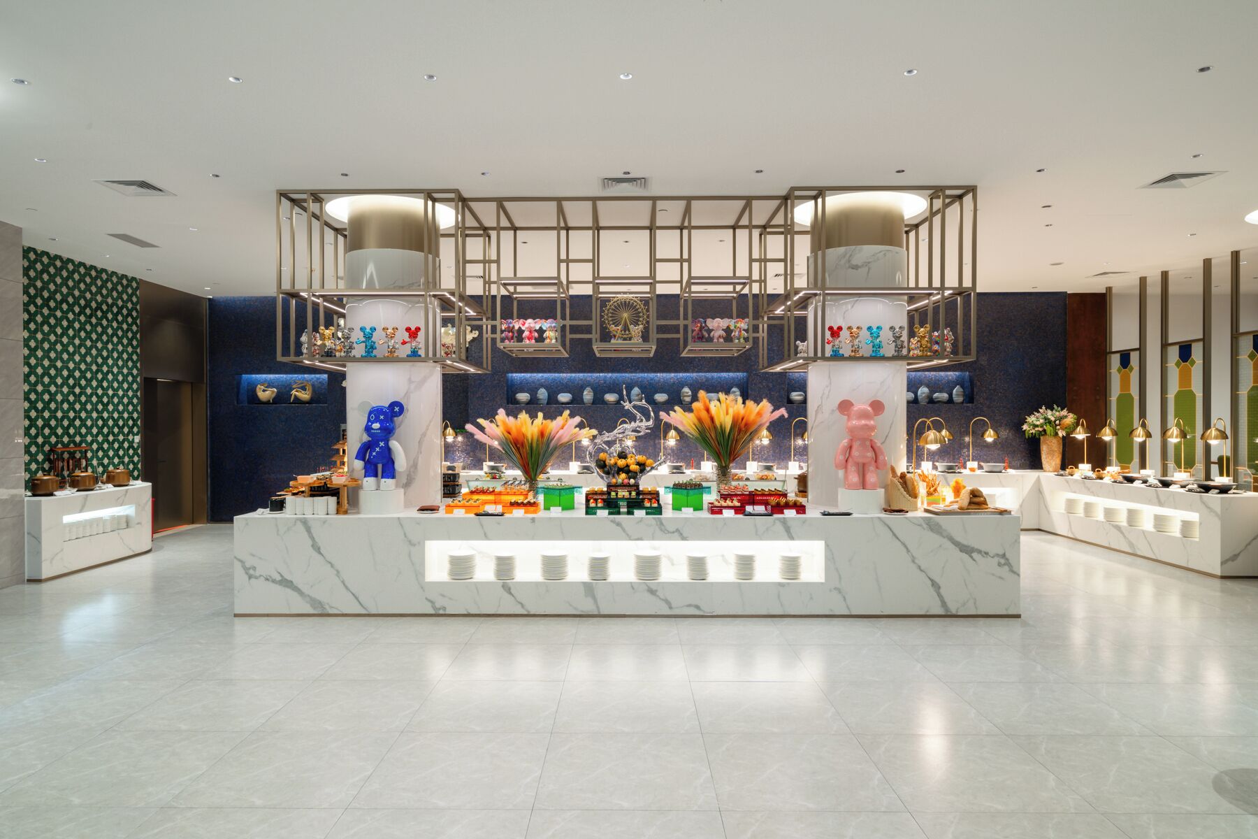 Un vestíbulo de hotel con un mostrador de recepción de mármol, estatuas decorativas de osos y una pared con diseño azulado.
