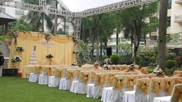 Un palco per matrimonio con uno sfondo giallo e sedie bianche con nastri dorati.