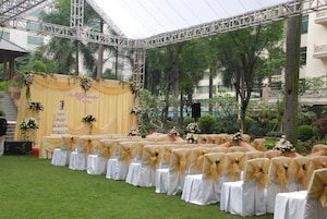 Un palco per matrimonio con uno sfondo giallo e sedie bianche con nastri dorati.