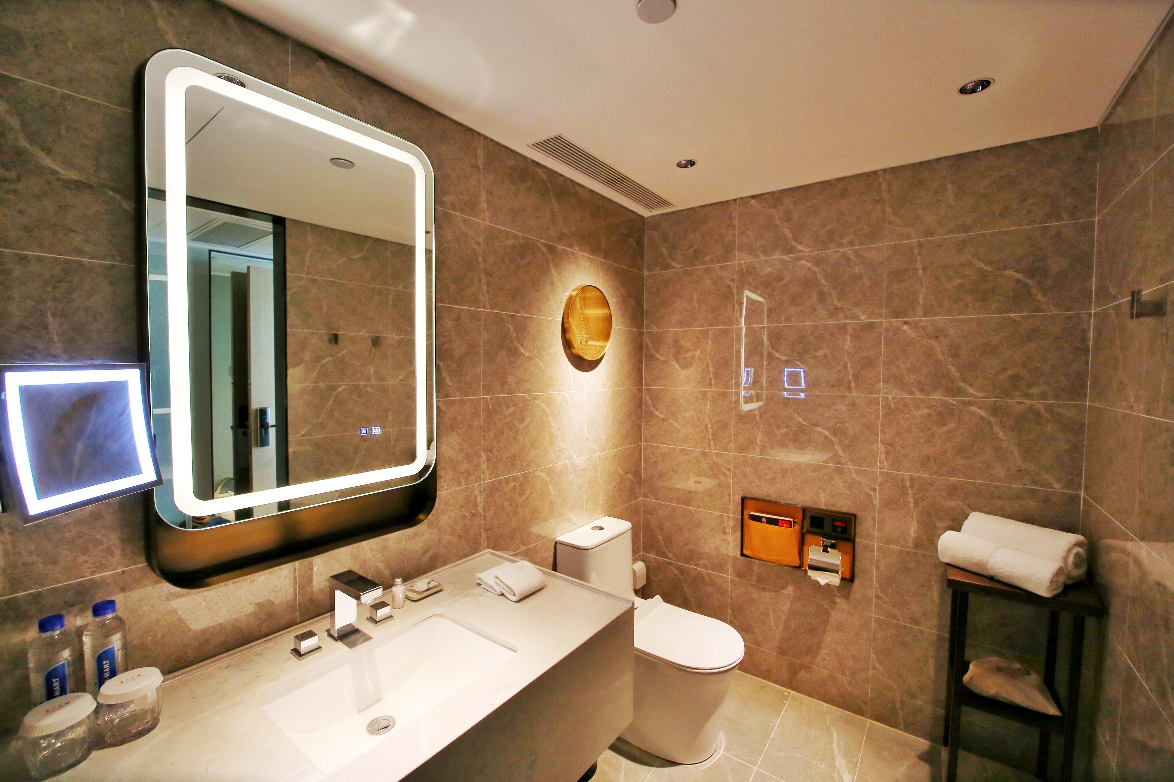 A modern bathroom with a large mirror, a sink, a toilet, and a towel rack.