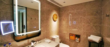 A modern bathroom with a large mirror, a sink, a toilet, and a towel rack.