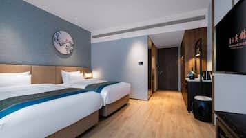 Habitación de hotel con dos camas, un adorno circular en la pared, un televisor y una pequeña zona de estar.