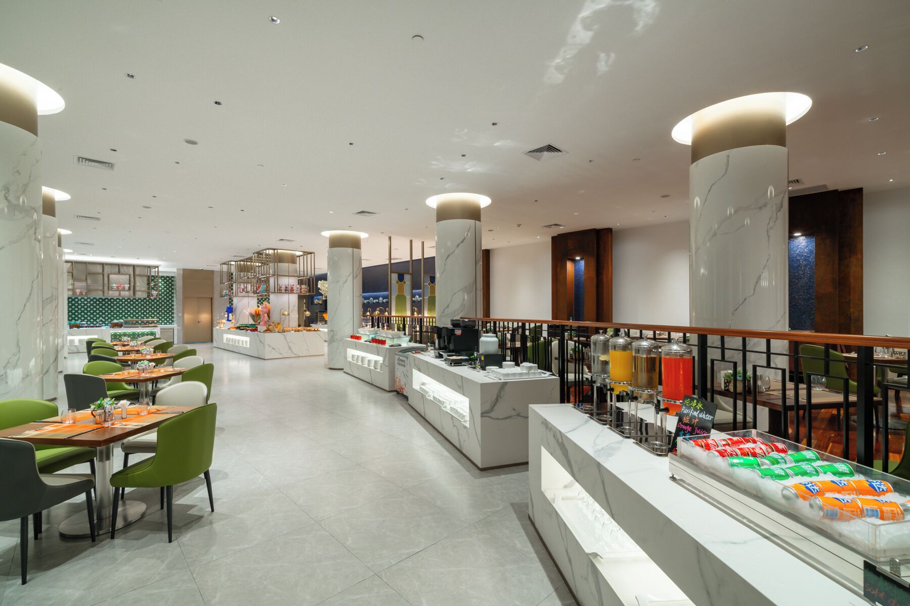 Eine moderne Hotelhalle mit Marmorsäulen, einer zentralen Rezeption und einem Buffetbereich mit verschiedenen Speisen.