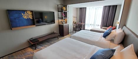 Une chambre d’hôtel avec deux lits, une télévision, un bureau et un balcon avec des rideaux.