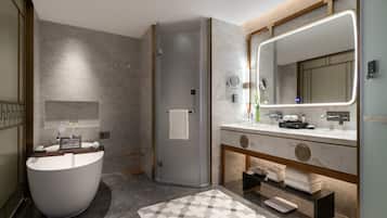 Un baño moderno con una bañera independiente, un espejo grande y un tocador con encimera de mármol.