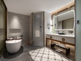 Un baño moderno con una bañera independiente, un espejo grande y un tocador con encimera de mármol.