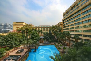 A hotel with a swimming pool surrounded by palm trees and a garden. - Dong Fang Hotel Guangzhou (Guangzhou)