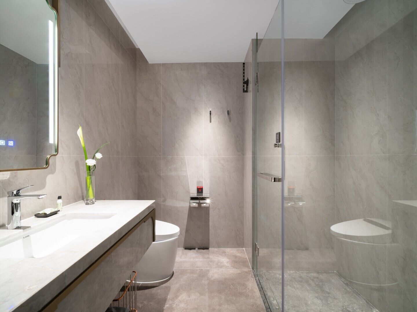 A modern bathroom with a large mirror, two sinks, a toilet, and a glass-enclosed shower.