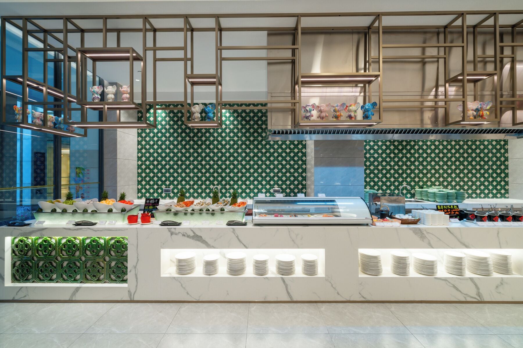A modern restaurant with a green patterned wall, a marble countertop, and hanging light fixtures.