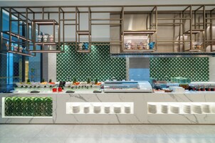 A modern restaurant with a green patterned wall, a marble countertop, and hanging light fixtures.