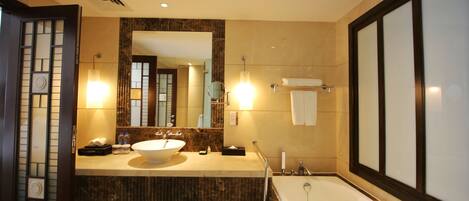 A modern bathroom with a large sink, mirror, and bathtub.