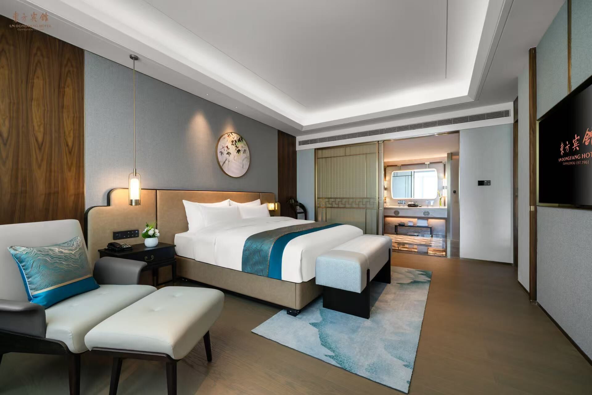 Et moderne hotelværelse med en stor seng, et skrivebord, en stol og et fjernsyn.