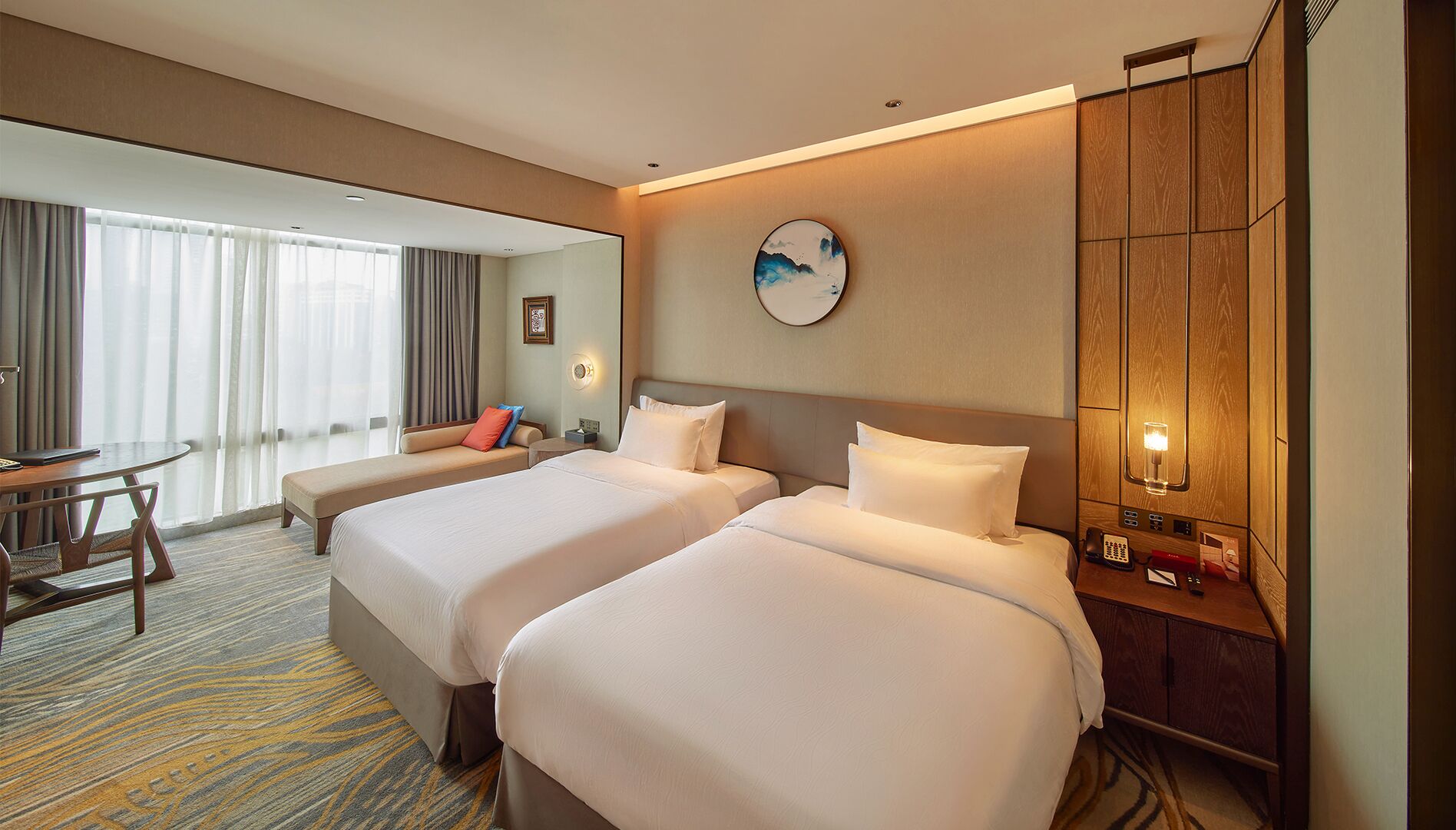 A hotel room with two beds, a desk, and a chair.
