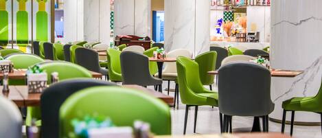 Un restaurant moderne avec des chaises vertes et grises, des colonnes en marbre et un design épuré et contemporain.