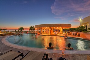 A pool area with a circular building, lounge chairs, and a sunset view. - Peñasco del Sol (Puerto Peñasco)