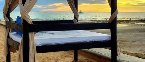 Un lit avec vue sur la mer et sur le coucher de soleil.