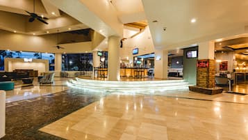 A spacious lobby with a central seating area, multiple screens, and a bar.