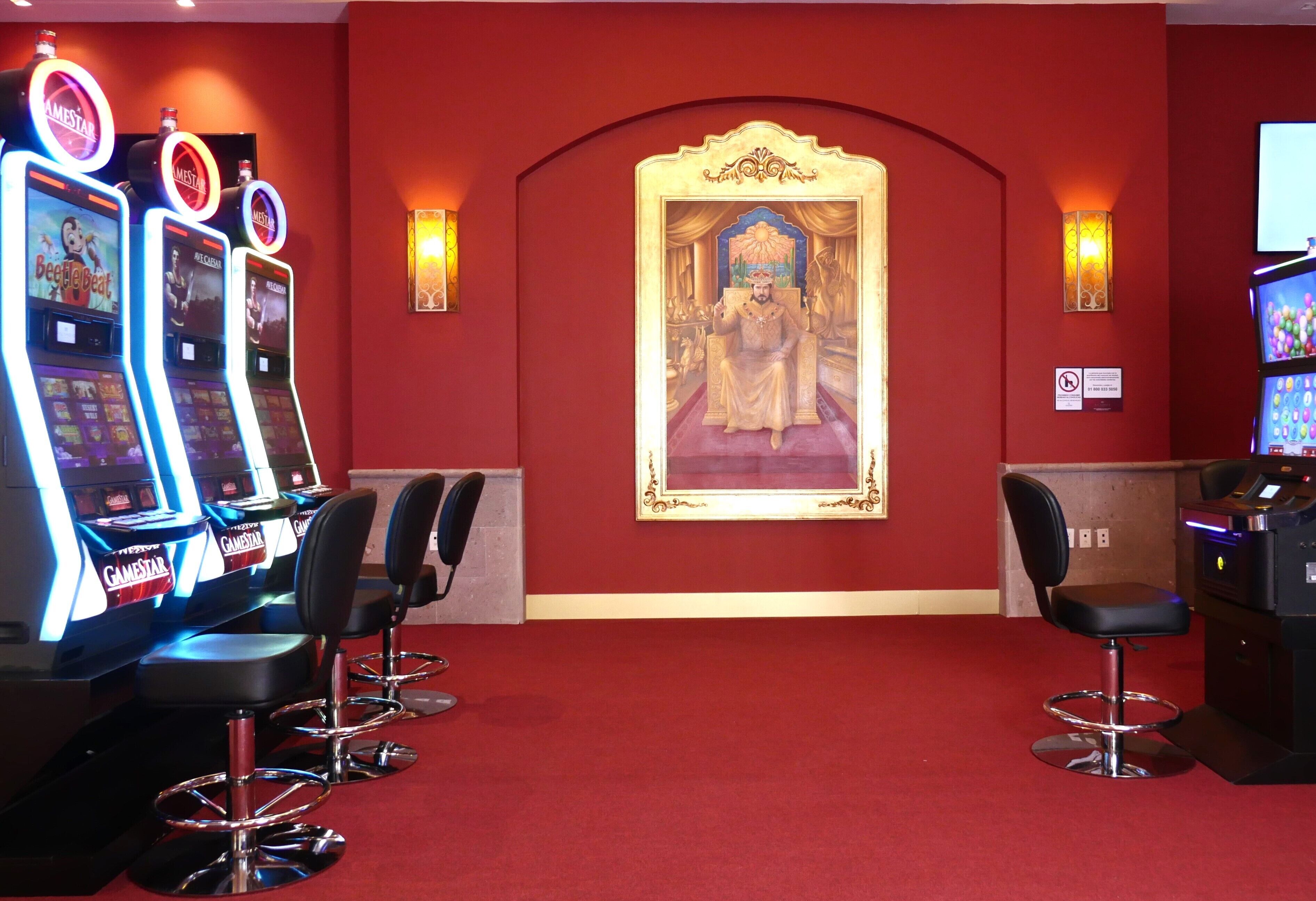 A gaming area with multiple arcade machines, a large framed painting, and bar-style seating.