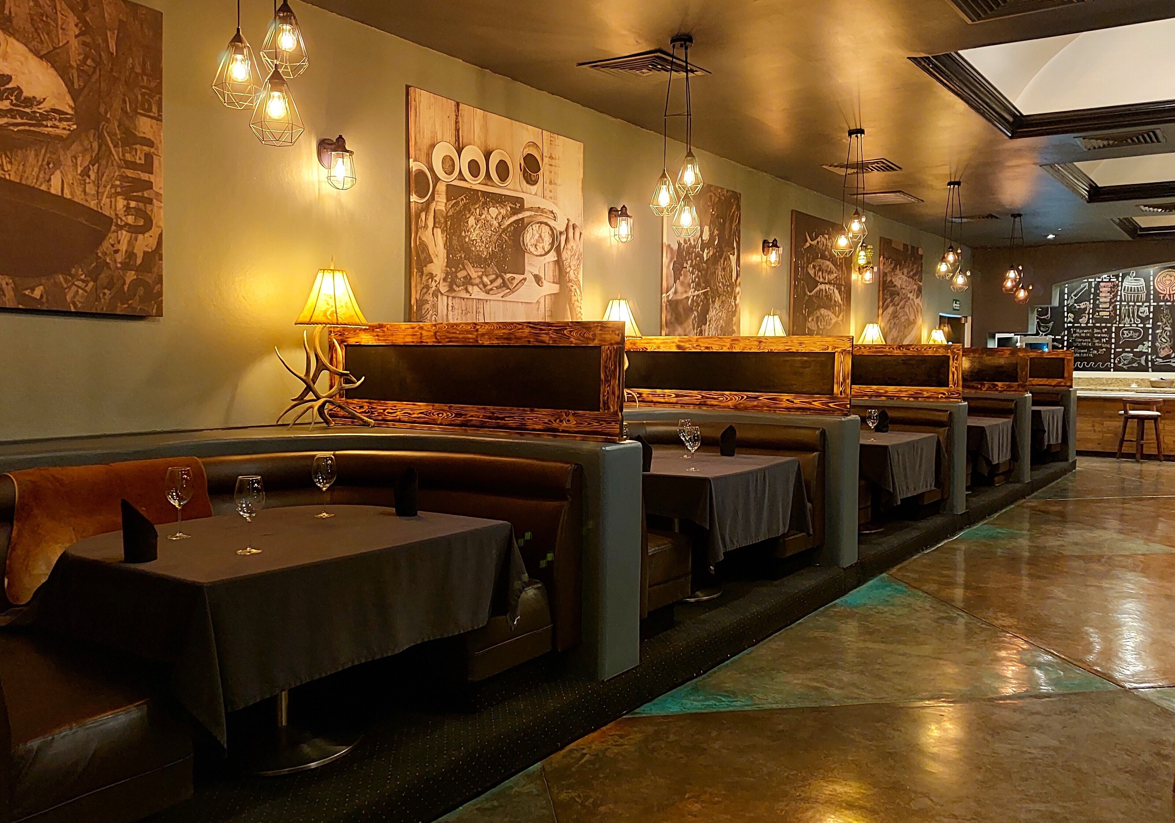 Un restaurante con mesas y cabinas, detalles de madera y decoración en las paredes.
