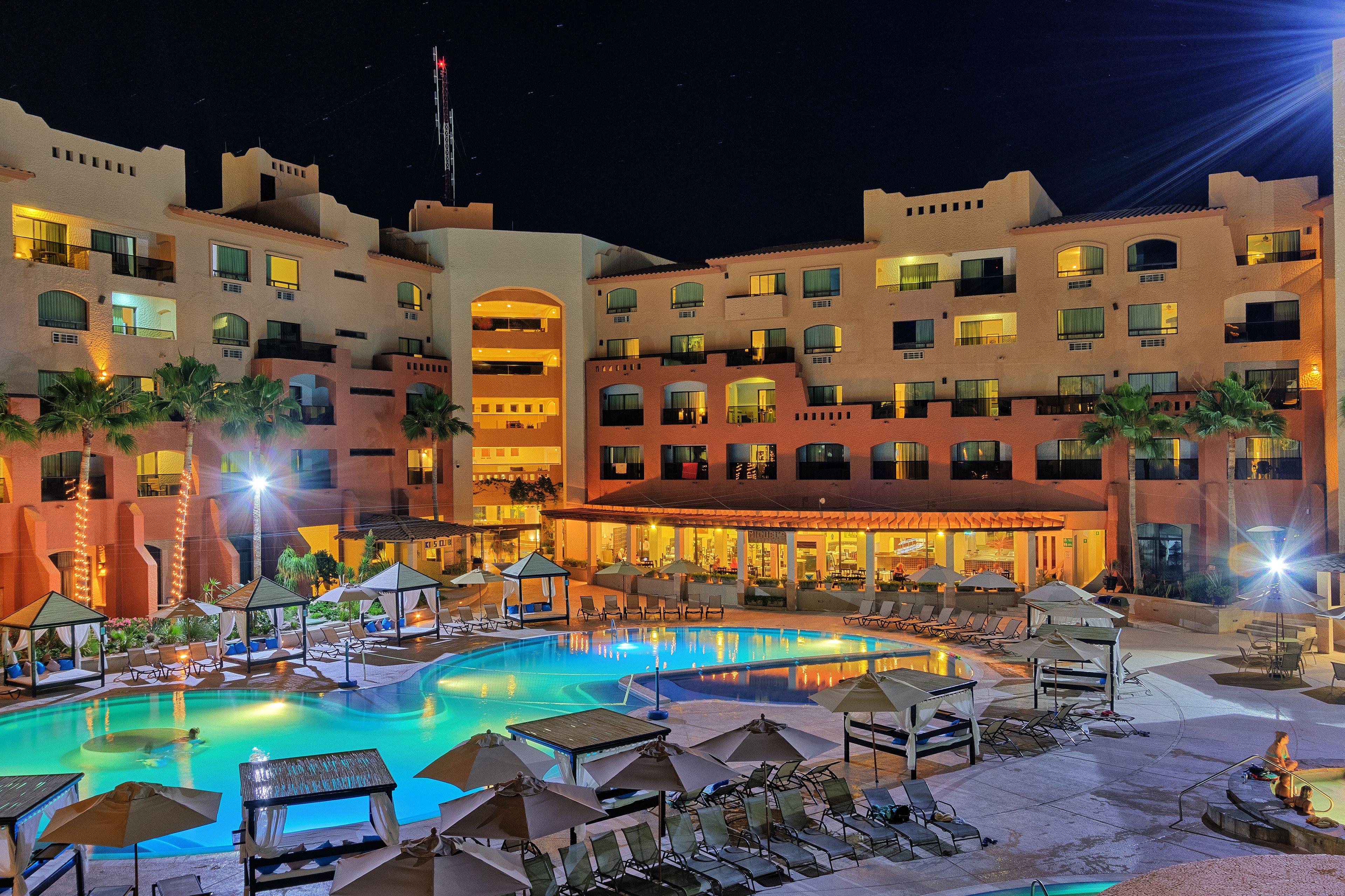 Un hotel con piscina, sillas de descanso y sombrillas.
