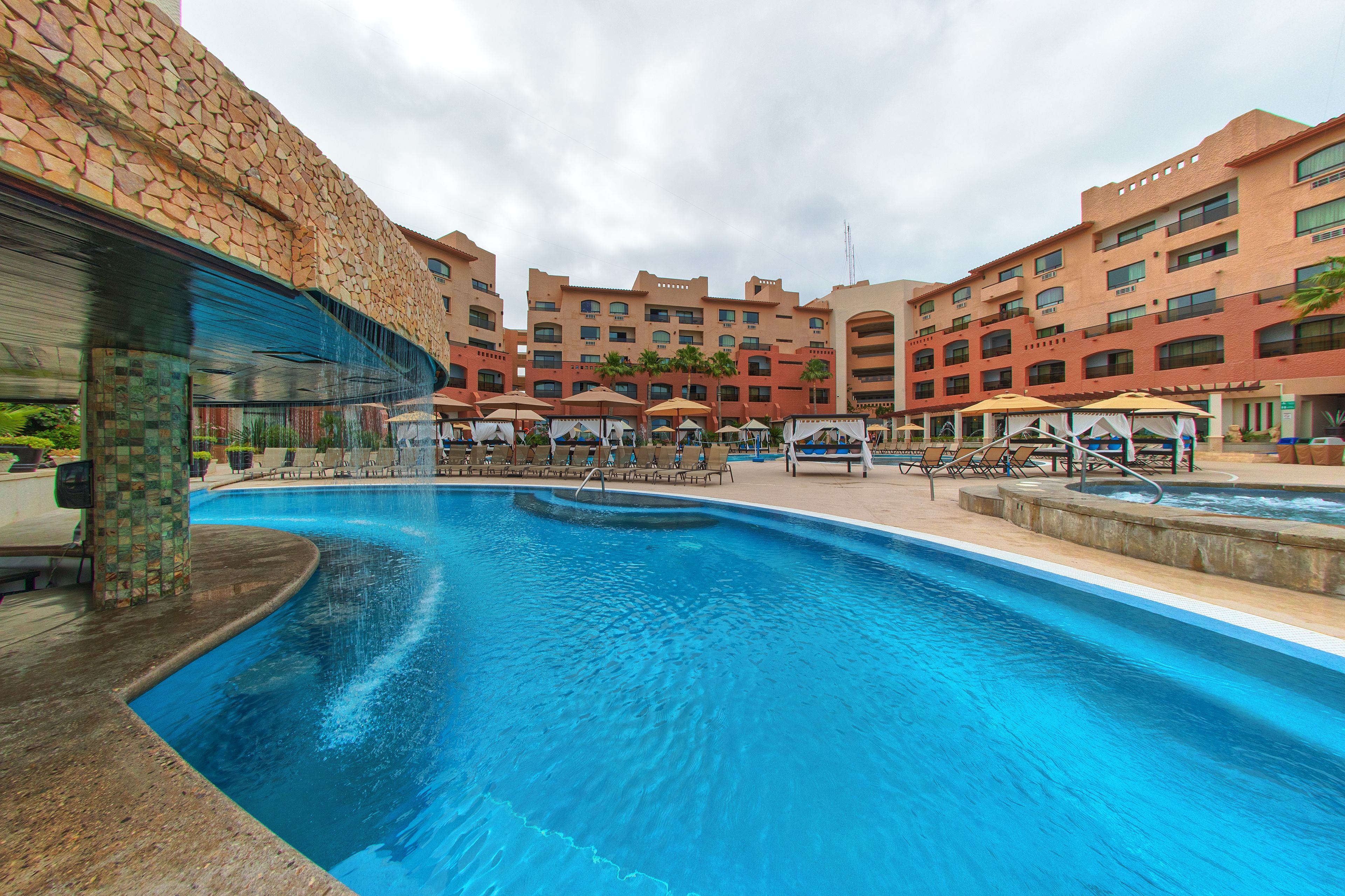 A hotel with a swimming pool, outdoor seating, and a stone facade.