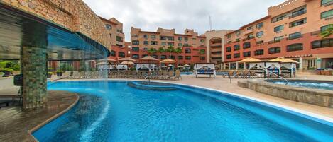 A hotel with a swimming pool, outdoor seating, and a stone facade.