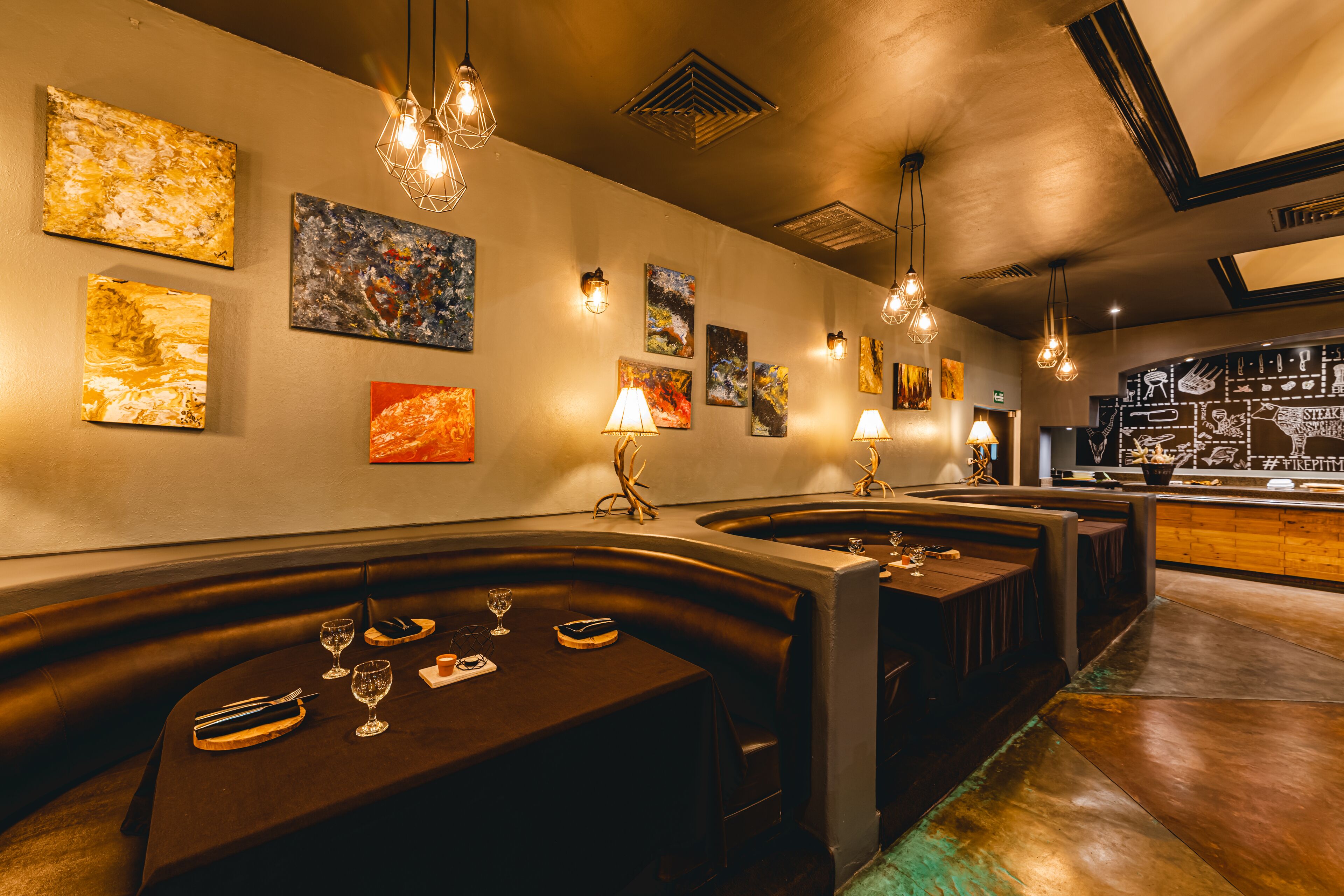 Un interior de restaurante con cabinas, mesas y decoración en las paredes.