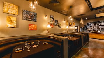 Un interior de restaurante con cabinas, mesas y decoración en las paredes.