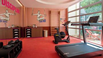 Un gimnasio con equipamiento de ejercicio, una cinta de correr y una pared con carteles motivacionales.