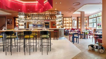 A bar area with multiple stools and a bar counter, a seating area with tables and chairs, and a large window providing a view outside.