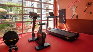 A gym with exercise equipment, a red carpet, and a large window with a view of the outside. - Urban Hive Paris (Paris)