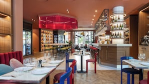 A restaurant interior with multiple dining tables, chairs, and a bar area with shelves of bottles. - Urban Hive Paris (Paris)