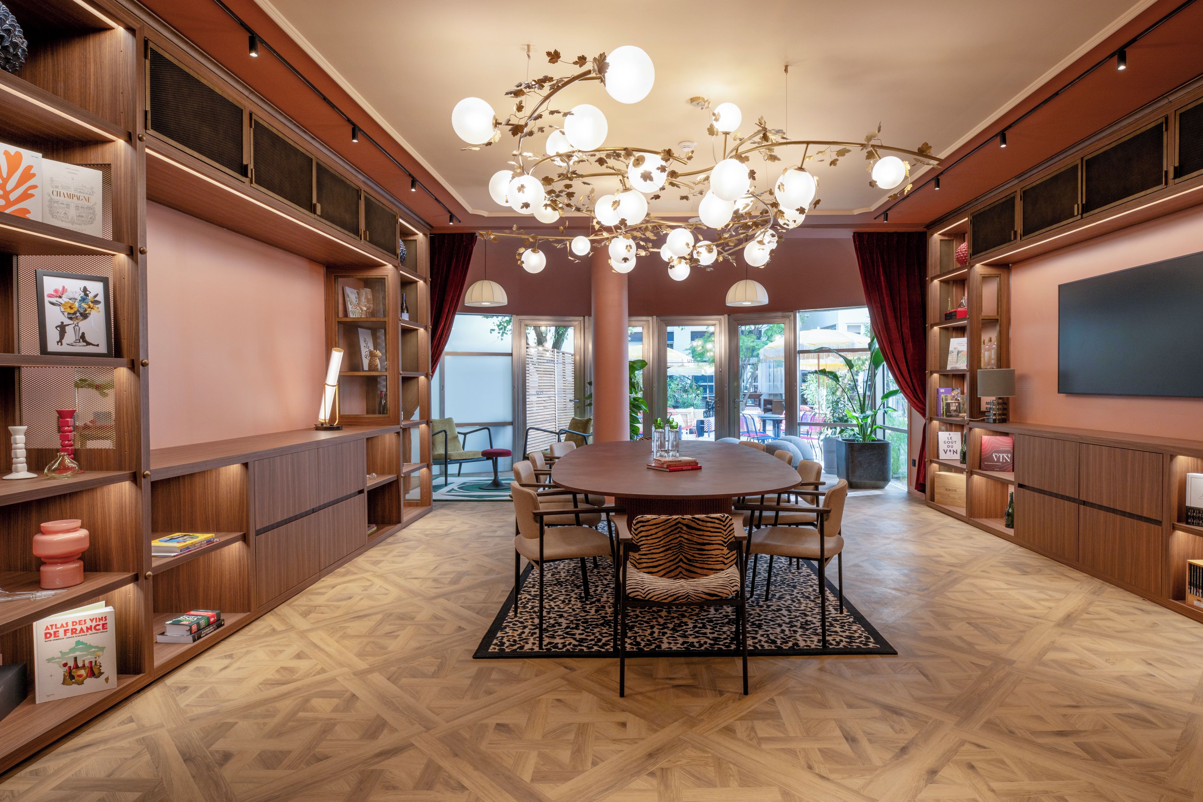 A room with a round table, chairs, bookshelves, and a decorative chandelier.